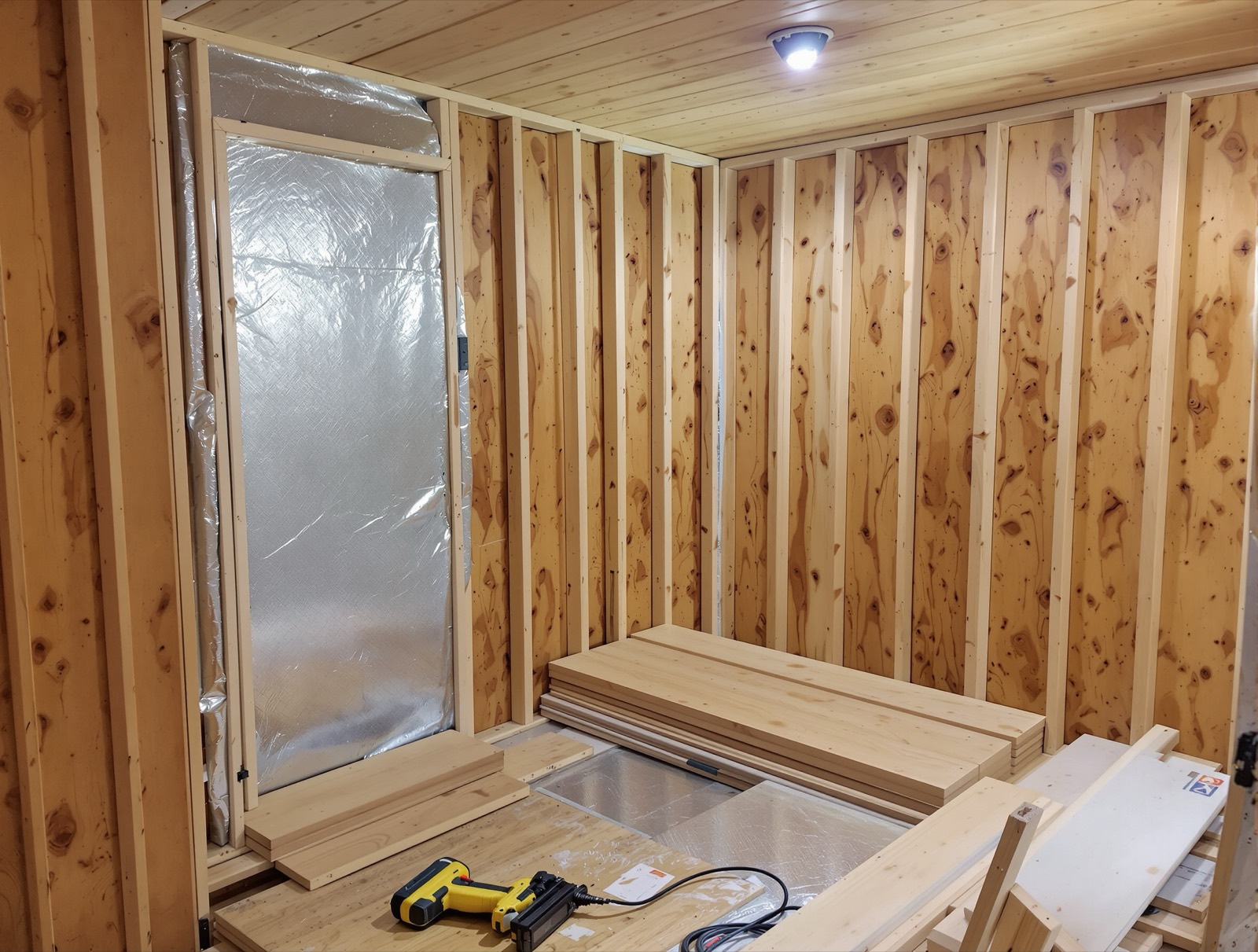 Cedar tongue and groove cladding half installed over foil vapor barrier