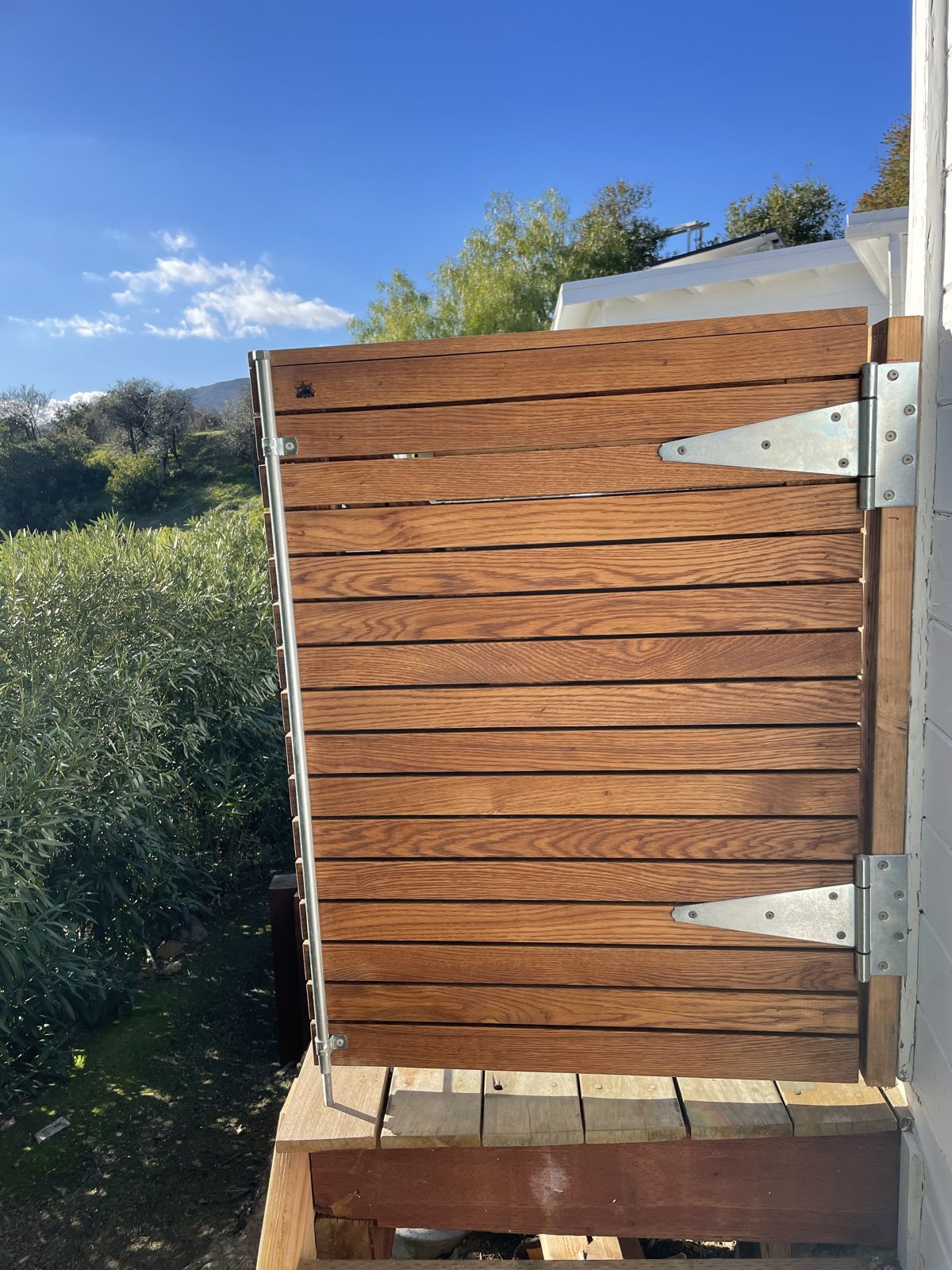 Hinged white oak equipment screen beside a deck